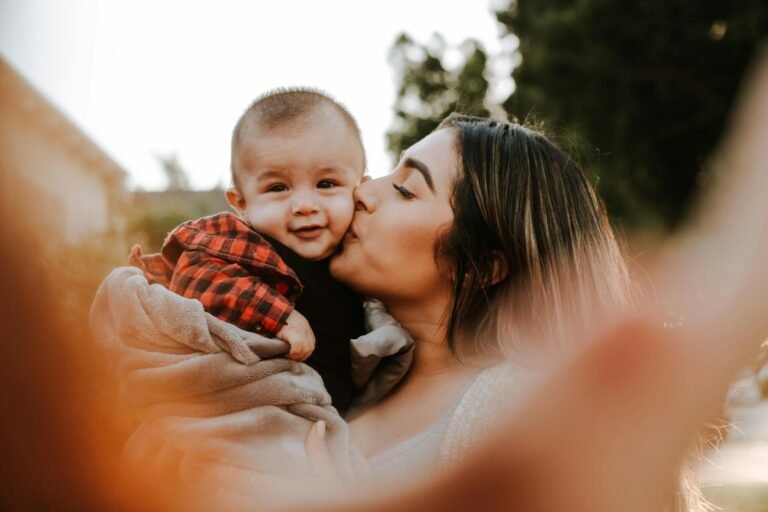 Mãe beijando o rosto do bebê, que sorri